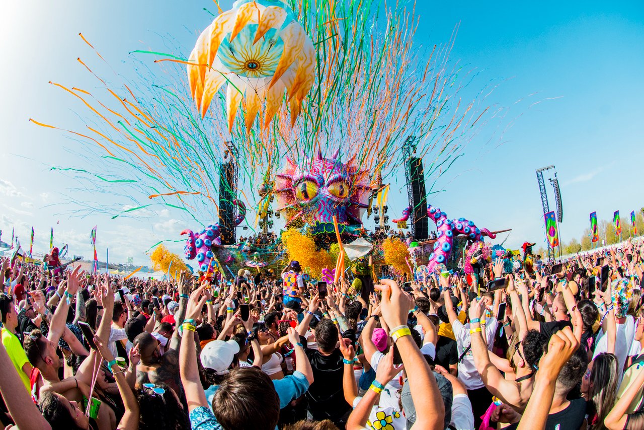 Serpentinas coloridas voando sobre o público da elrow, com o palco do monstro ao fundo