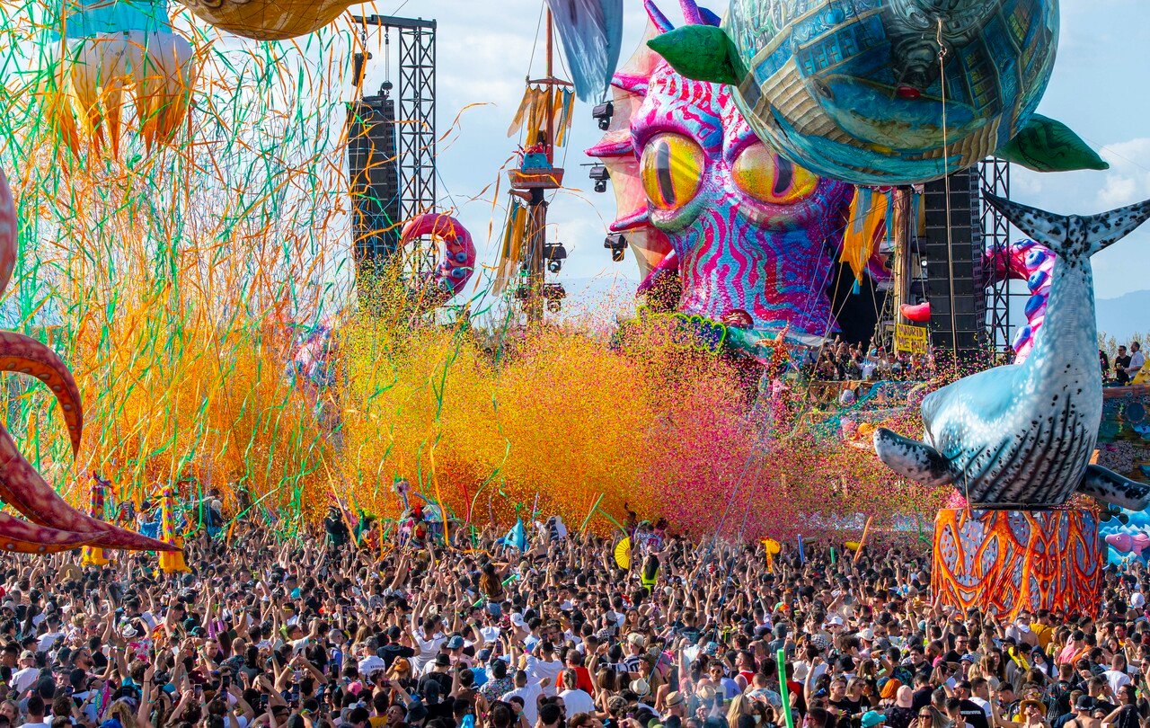 Chuva de confetes e serpentinas sobre a pista, com os infláveis gigantes da elrow ao fundo