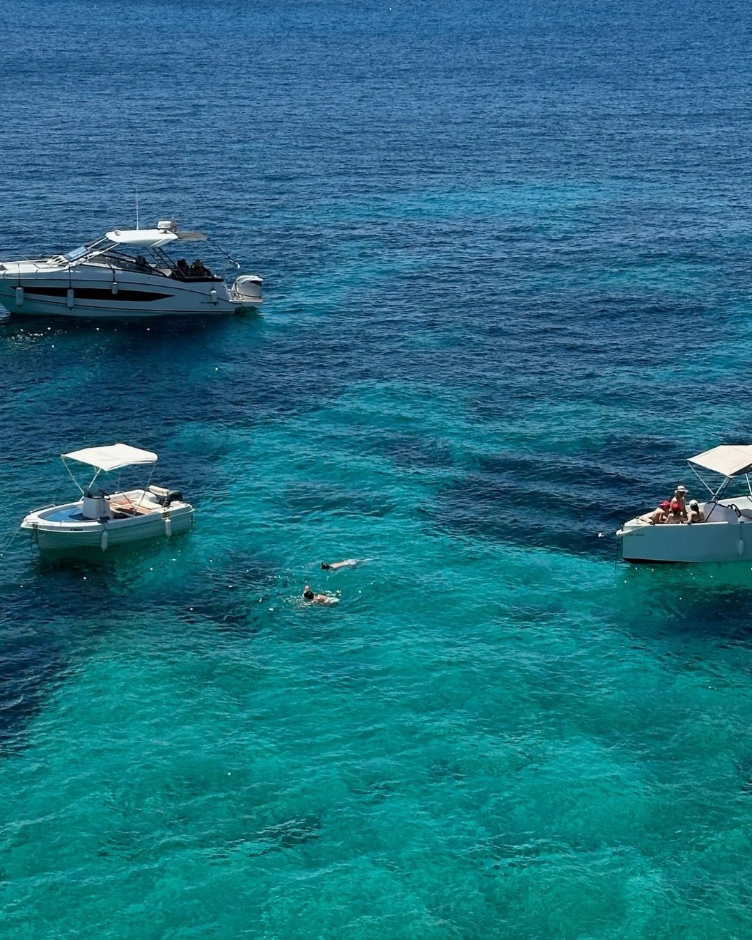 Barcos ancorados em água azul-turquesa transparente no litoral de Ibiza