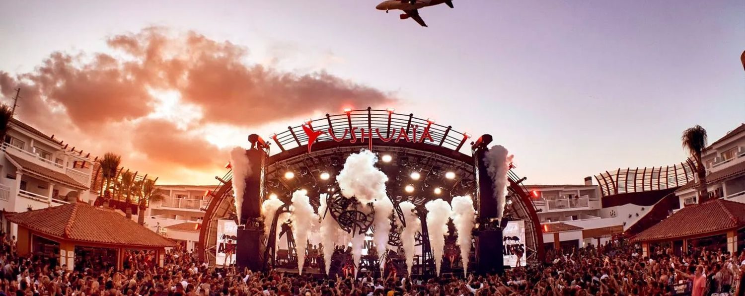 Palco do Ushuaïa Ibiza lotado no fim da tarde, com jatos de CO2 e avião cruzando o céu
