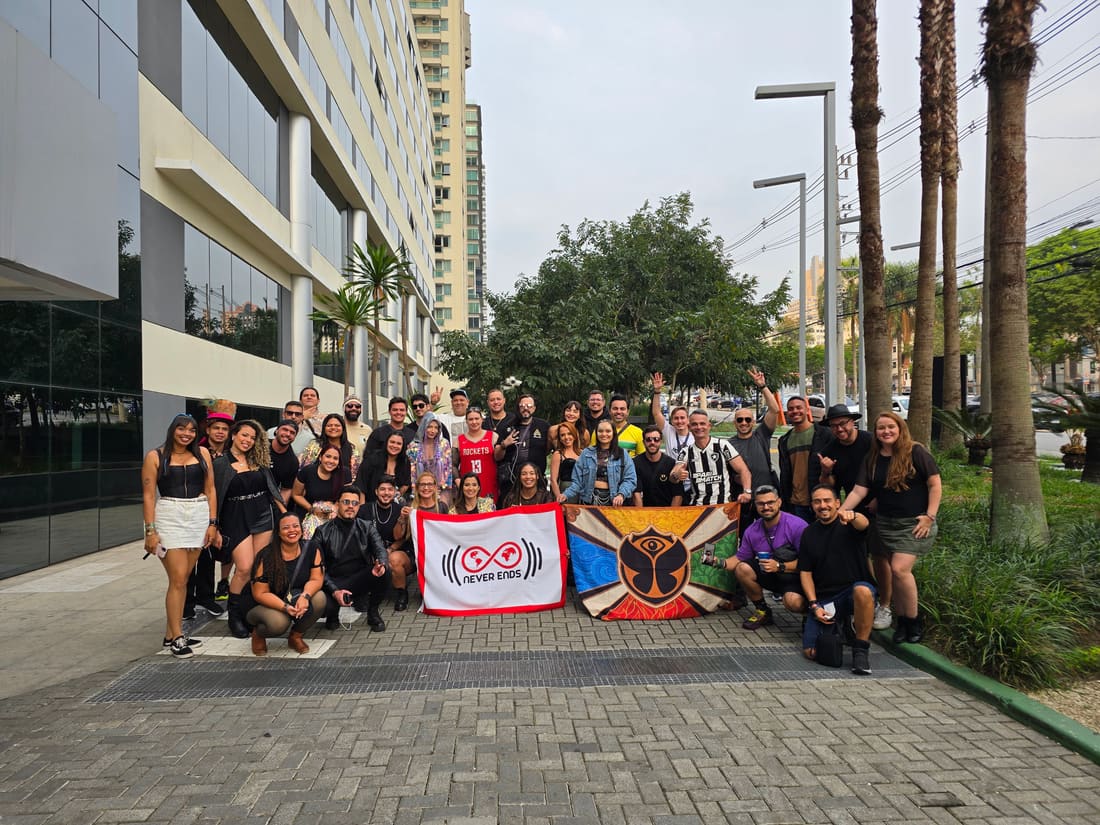 Viajantes da Never Ends reunidos na saída do hotel em 2024, com as bandeiras da agência e do Tomorrowland Brasil.