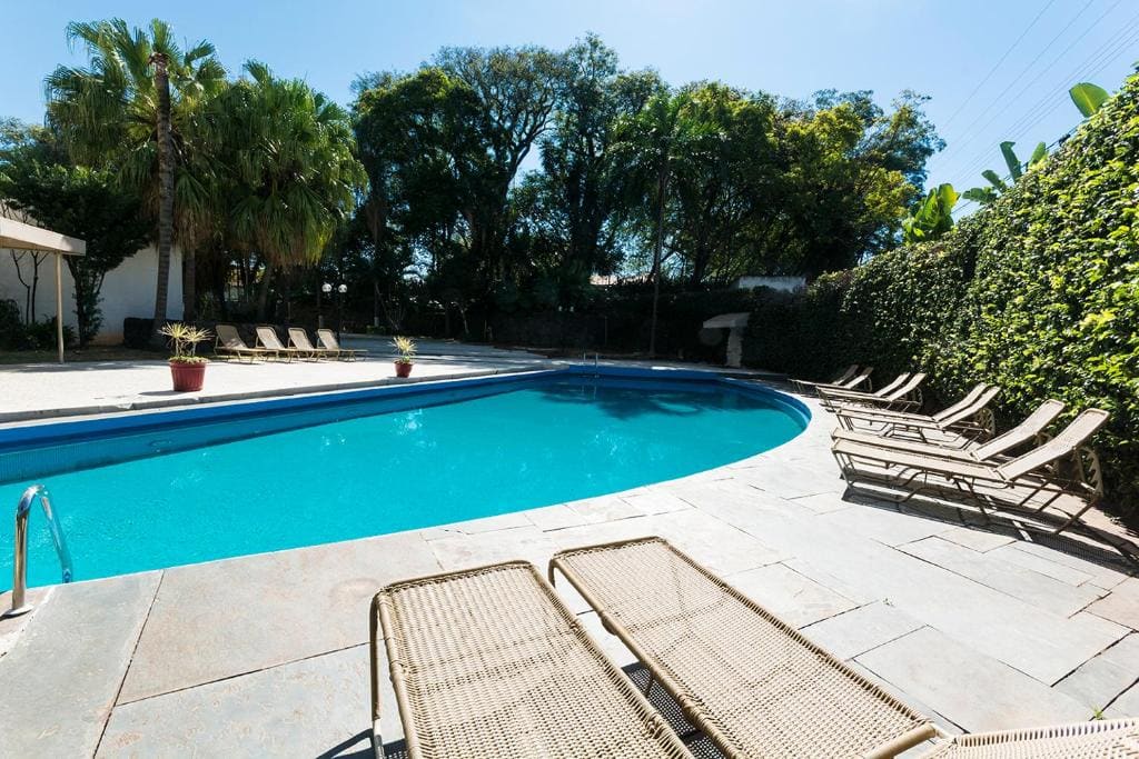 A piscina do Hotel Never Ends, entre palmeiras e a cerca viva, com as espreguiçadeiras no deque de pedra. É aqui que o café da manhã e a música de cada manhã acontecem.
